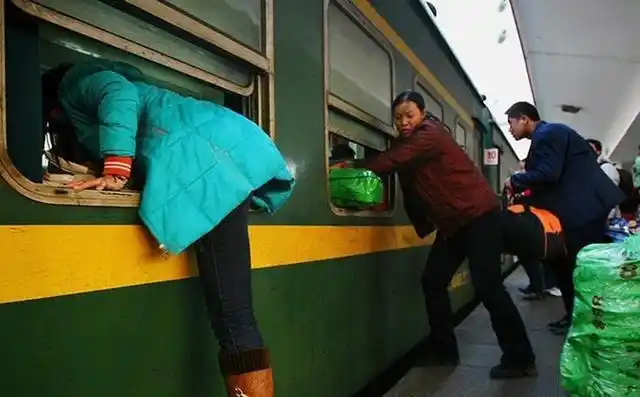 外出务工者爬窗户赶火车为上班多赚钱 车厢内已经被晒满了外出打工者
