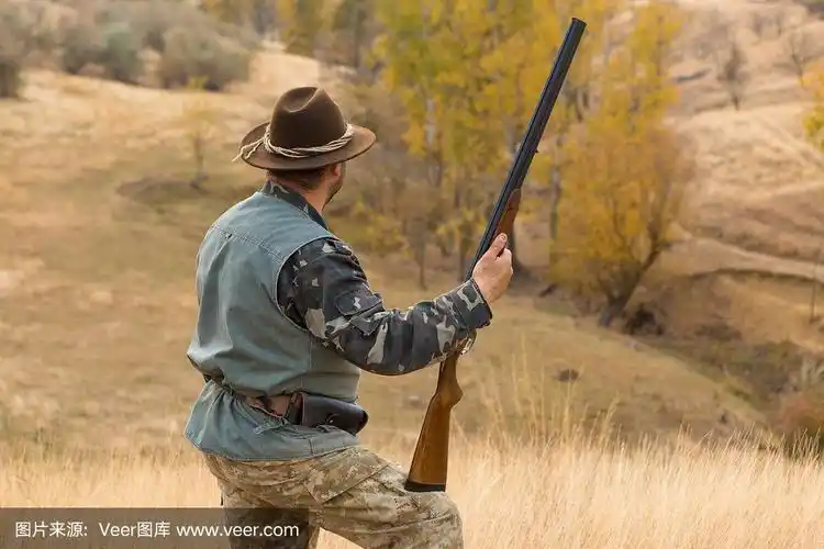 猎人戴着帽子,拿着枪在草原上寻找猎物,瞄准猎物