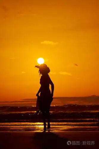 夏日夕阳下,沙滩上的年轻女子剪影