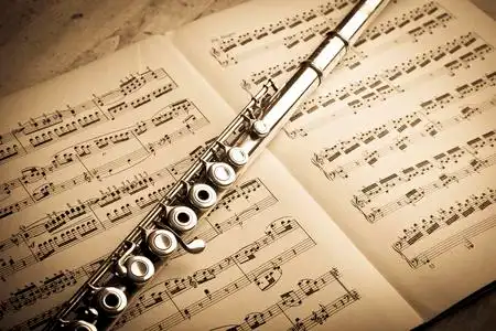 上的歌放在乐谱上的旧小提琴银色长笛长笛乐谱上一只手指在钢琴上按键