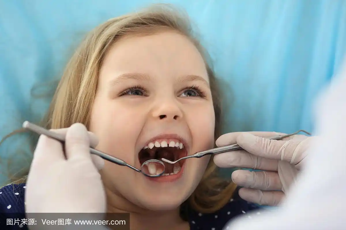 小女孩张大嘴巴坐在牙科椅上接受医生的口腔检查.拜访牙医的办公室.