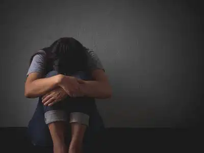 悲伤的女人抱着她的膝盖和哭泣.悲伤的女人独自坐在空荡荡的房间照片