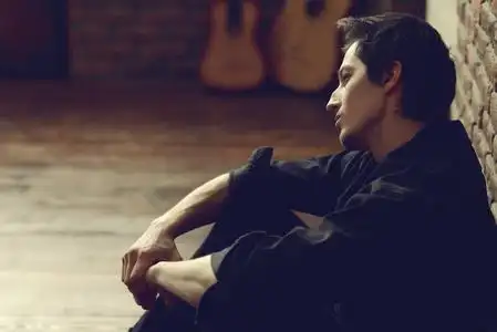 男子男士一个悲伤, 沉思的年轻男子的肖像.阁楼风格的内部.