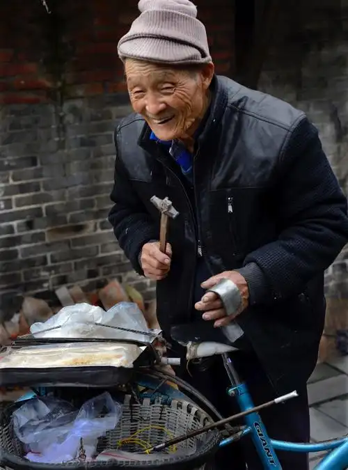 大邑新场镇一位卖叮叮糖的老者谦卑得近乎谄媚