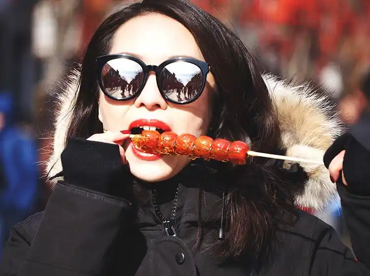 寒风中,一名女游客正享受冰糖葫芦.