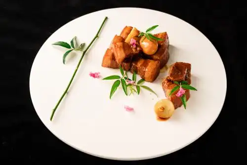 黑色背景上精致摆盘的红烧肉