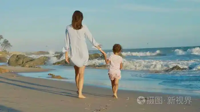 母亲与婴孩在海海岸散步与牵手