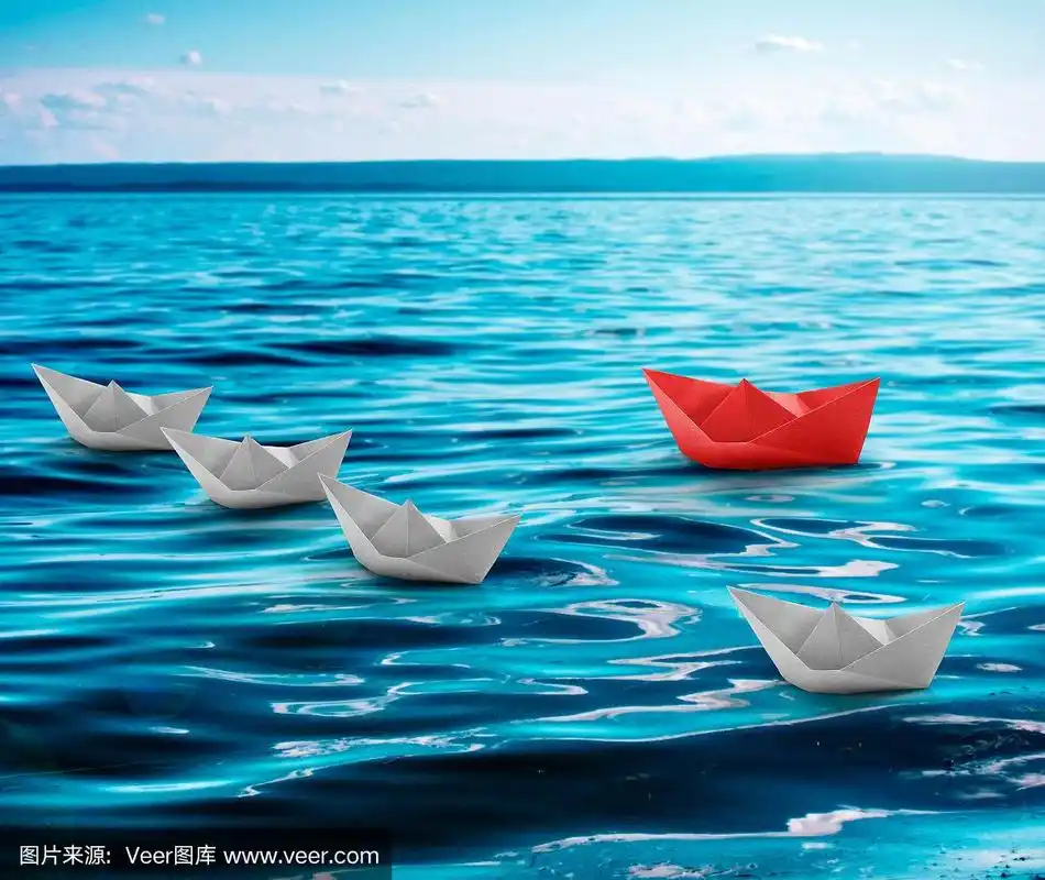 漂浮的纸船折纸与一个红色的在绿松石水海.