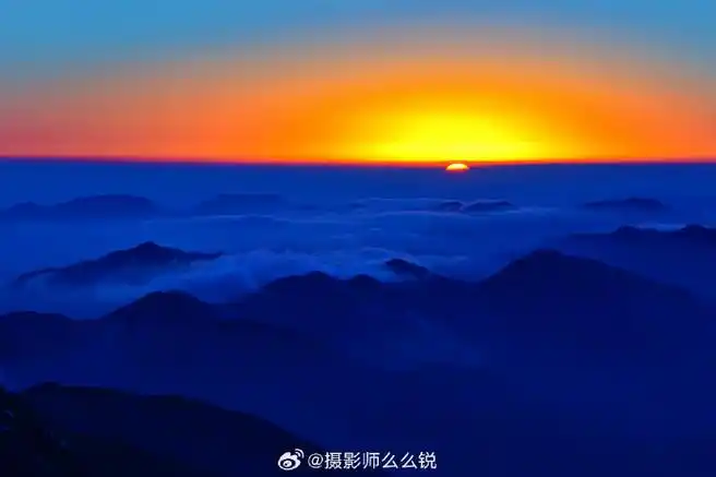 太阳刚刚跃出地平线,天际线先是一抹橙色光晕,然后开始冒头的太阳,泛