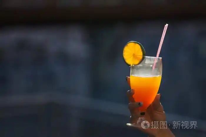 在户外玻璃手拿着一个橙色的鸡尾酒
