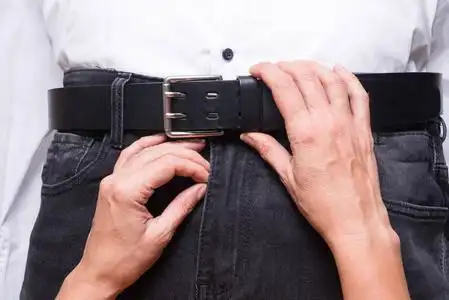 女人用手解开男人牛仔裤上的皮带照片