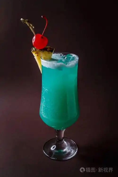 蓝色鸡尾酒樱桃和菠萝片在优雅的深褐色背景的玻璃