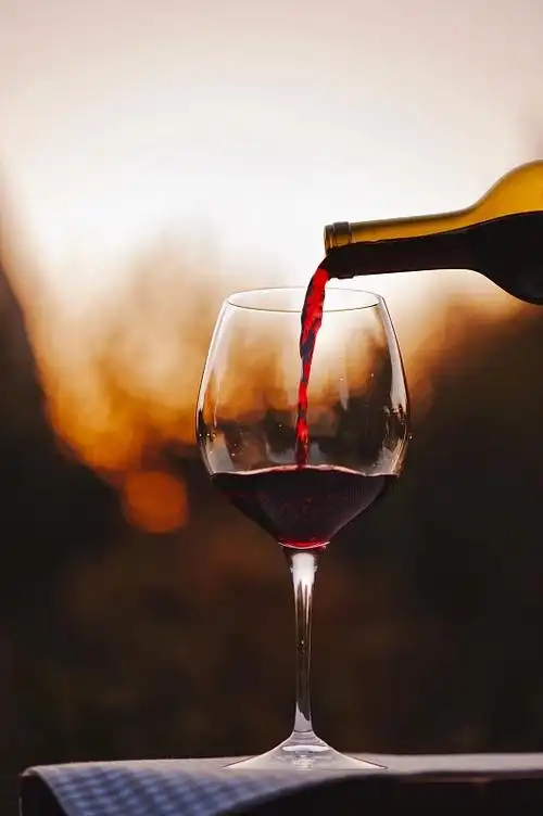 在日落时,葡萄酒倒在桌子上的酒杯的特写图片下载
