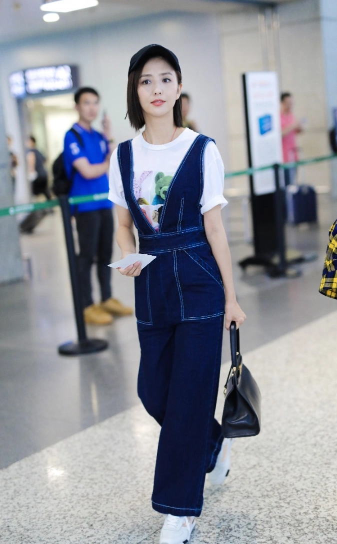 佟丽娅穿牛仔背带裤内搭白t现身机场 笑容迷人露标志性小漩涡