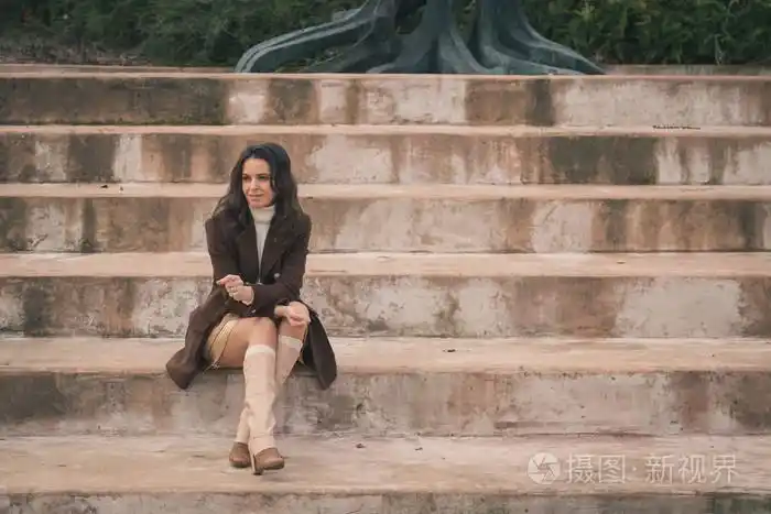 美丽的年轻女子坐在混凝土台阶上