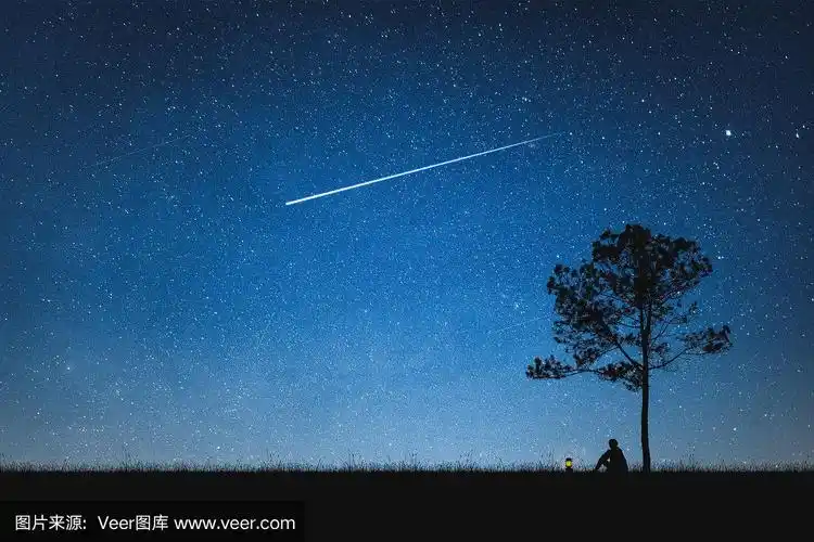 一个人的剪影坐在山上和夜空与流星.单独的概念.