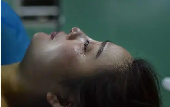 图为飞雨被移到推车上,术后疼痛让她有些难受.