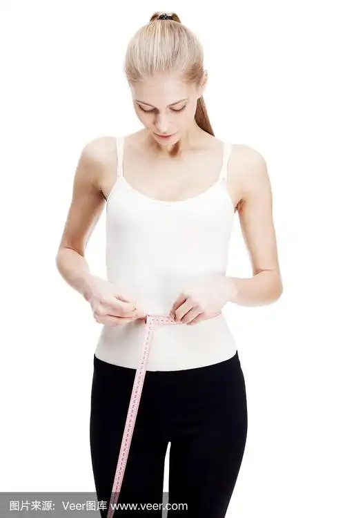 年轻的金发女人测量腰围孤立在白色