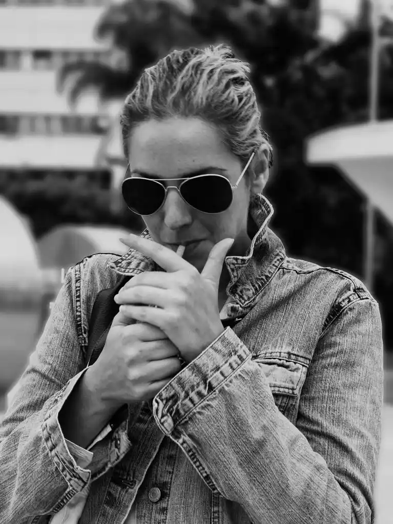 香烟点火,吸烟的牛仔夹克和太阳镜,黑色和白色的年轻女子的画像射击