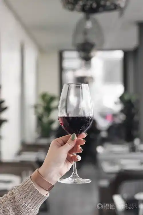 女性手捧酒杯在咖啡厅桌上的红酒