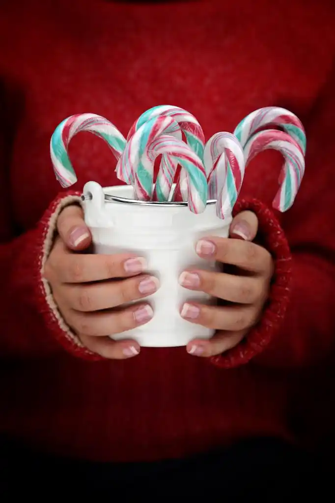 女性手里拿着拐杖糖白色桶