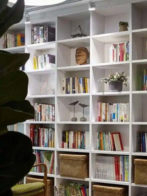 放弃了固有的沙发背景墙,而是用白色木板打造了一面书架,让客厅兼具了