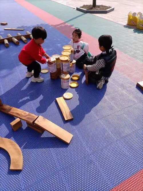 图中的三个孩子,在一起用奶粉罐和盖子就一起搭建了城堡.