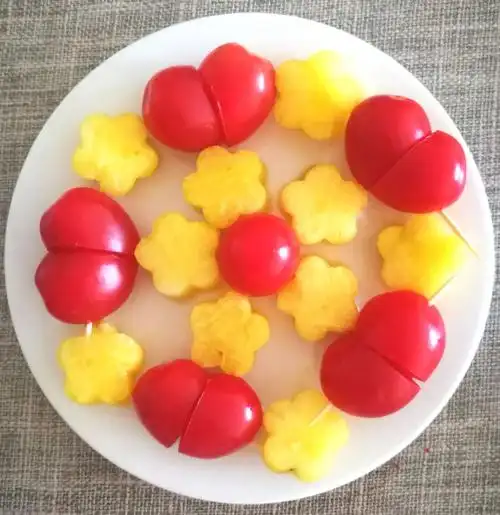 圣女果顶部斜切一小半,然后两个用牙签串起来是一个心形,配黄馕造型