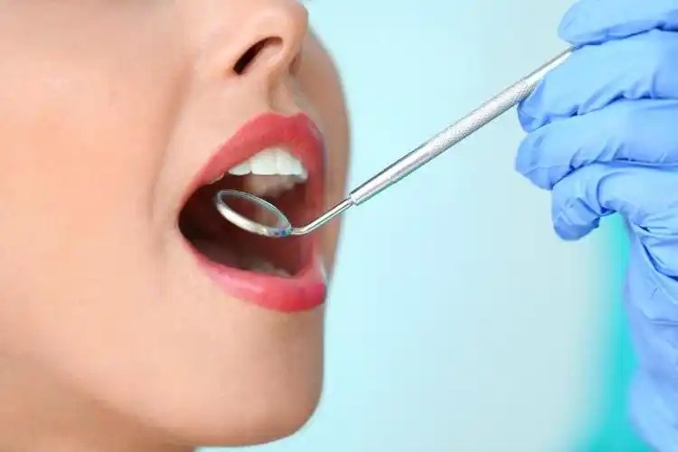 带蓝色手套的牙医用仪器检查美女牙齿