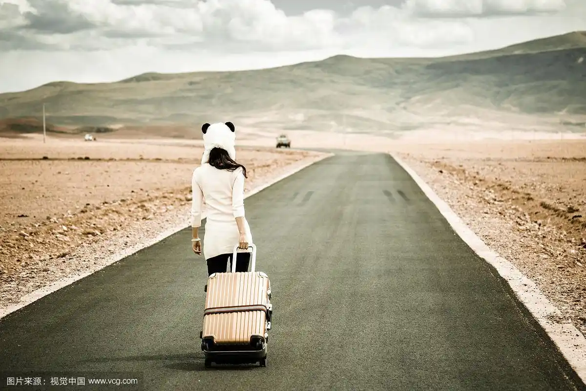 独自拖着行李箱在马路上行走的女孩背影