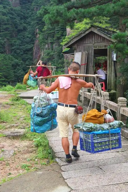 安徽九华山上的挑夫肩上是百斤重担游人纷纷行注目礼