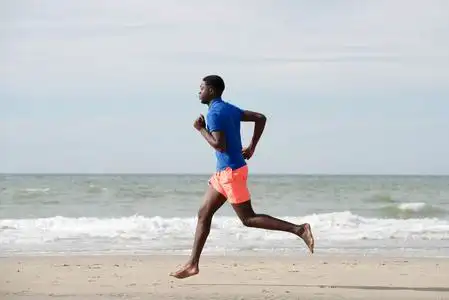 奔跑侧面健康的非裔美国人在海滩上奔跑的全身侧面肖像照片