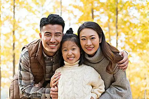 快乐的一家三人秋游漫步银杏林穿红色毛衣拜年的祖孙三人三个人,举起