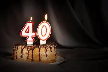 生日巧克力蛋糕,上面插着40号白色蜡烛.黑底黑布照片