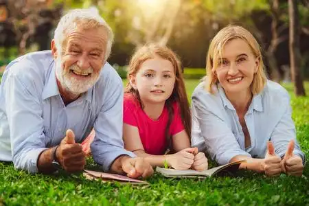 幸福的家庭一起看书,躺在公共公园的绿草上.