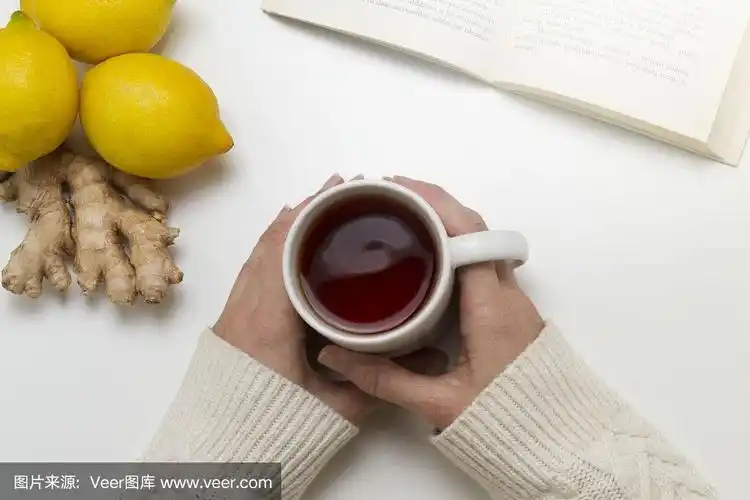 女人手里拿着一杯茶.旁边有一本书