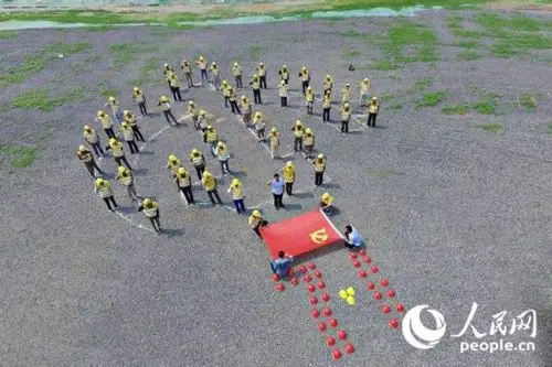 50余名建筑工人着统一工作服,站成"党徽"图案,面对党旗重温入党誓词