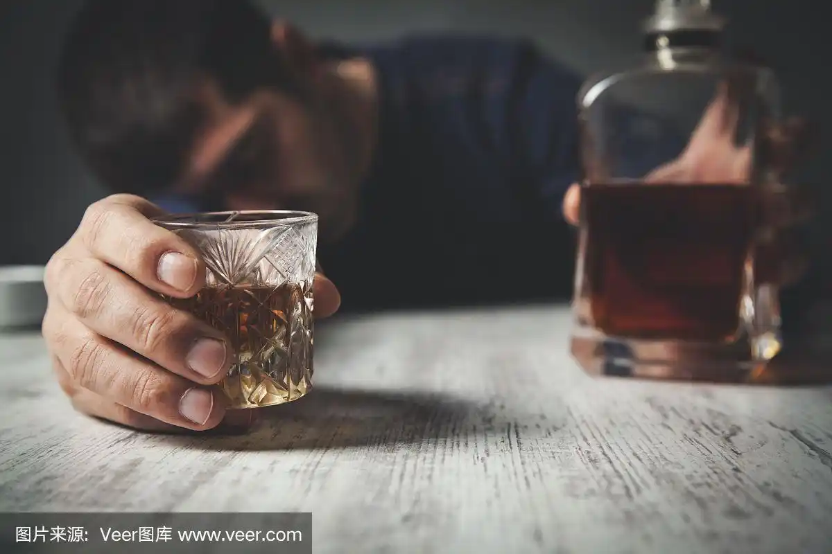 男人手里拿着威士忌酒瓶和玻璃杯