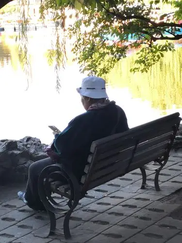 这位老人孤独的坐在湖边看着手机,可能是看着手机里的儿女在干什么?