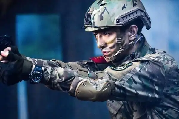 金瀚身穿军装,脸涂迷彩隐匿在丛林中.