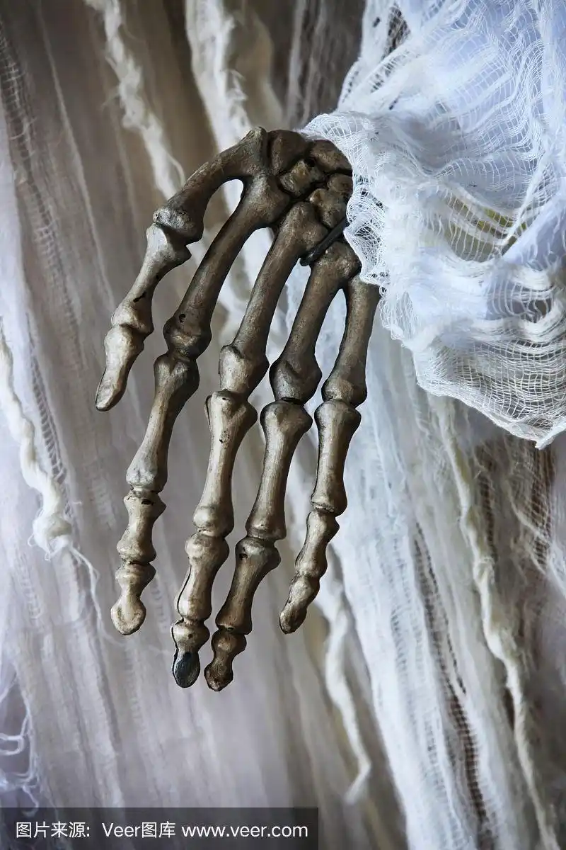 一只骷髅手在一件旧白裙子的背景上