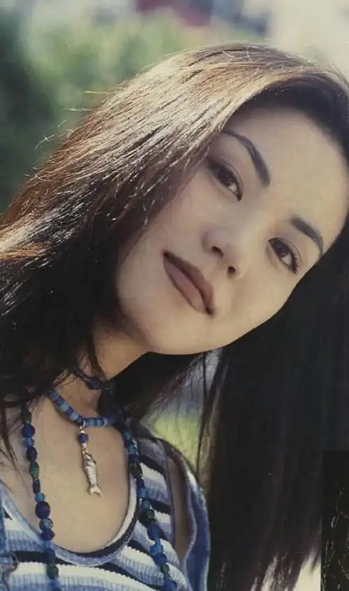 照片中王菲身着条纹背心搭背带裤,脖子上还戴着看似廉价的塑胶项链,大