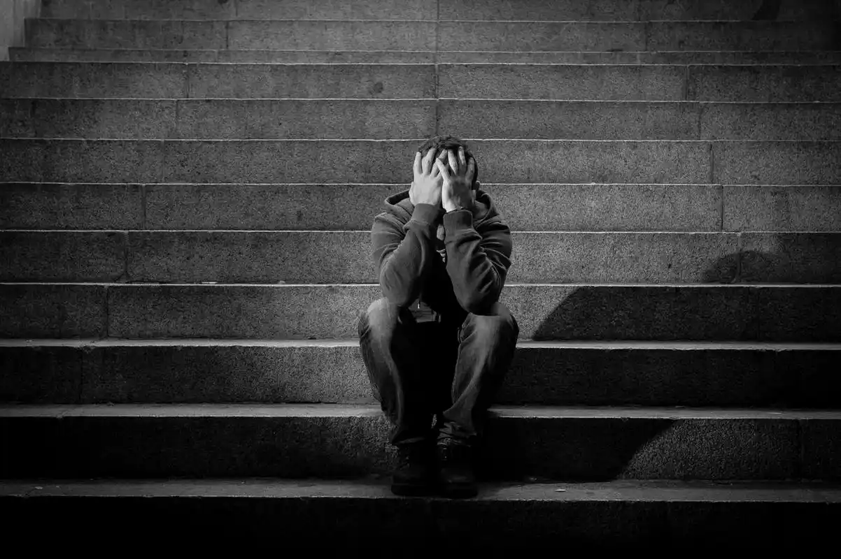 男子捂着脸坐在阴暗楼梯上孤独的男人失败难过烦躁恼火烦躁无奈后悔