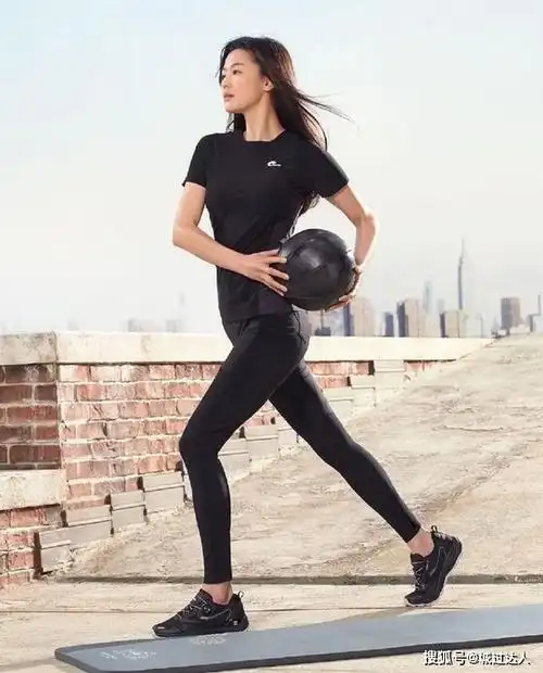 照片中,全智贤身穿黑色短袖以及健身裤,脚踩运动鞋站在室外的瑜伽垫旁