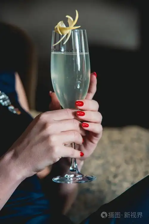 用红色的修指甲在女人手中的法国鸡尾酒.豪华酒店大堂酒吧.