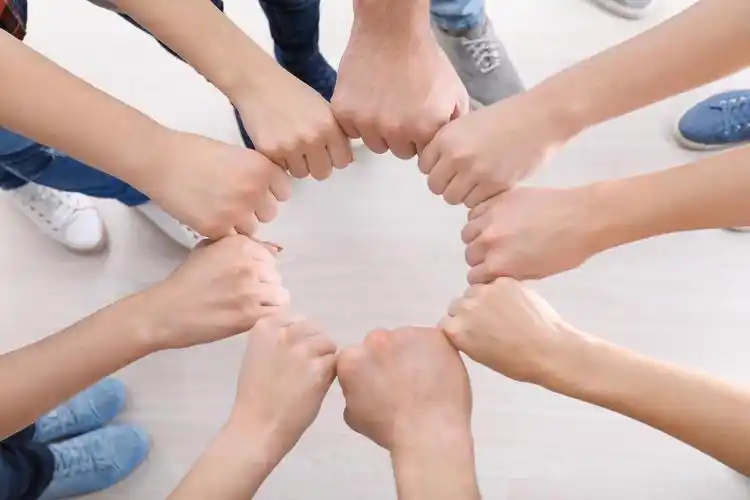 年轻人把拳头放在圆圈里作为团结的象征团队加油团结拳头团结手势激励