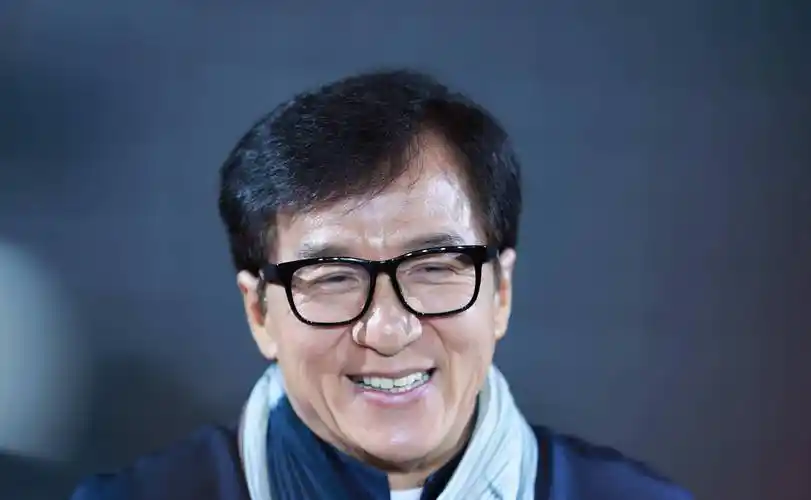 成龙在视频中穿着黑色中山装,发型处理得当,戴着黑色眼镜,整个人看