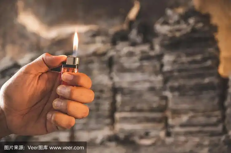 靠近点,手拿打火机在燃烧的背景上点火.