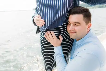 特写肖像开朗的年轻人抱着他怀孕的妻子的肚子.