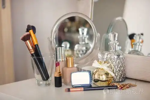 化妆艺术家香水,刷霜和其他化妆品与玫瑰近镜子在桌子上.